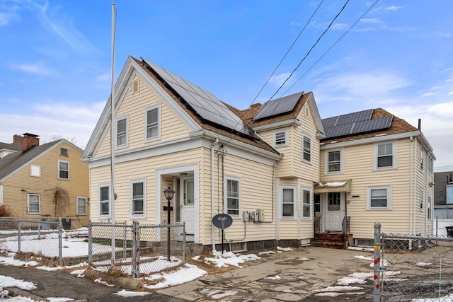 view of front of home featuring a fenced front yard, entry steps, a gate, and solar panels