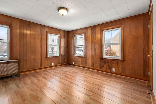 unfurnished room featuring radiator heating unit, baseboards, and light wood-style flooring