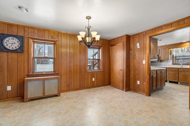 unfurnished dining area featuring wooden walls, stone finish flooring, and radiator