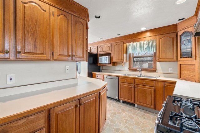 kitchen featuring light countertops, stainless steel dishwasher, white microwave, gas stove, and a sink