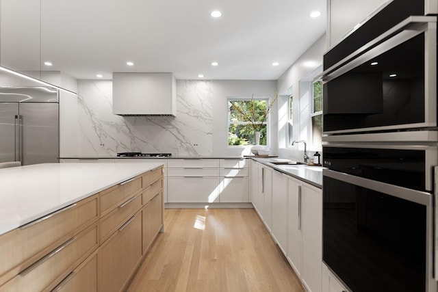 kitchen with sink, decorative backsplash, light brown cabinetry, white cabinets, and custom range hood