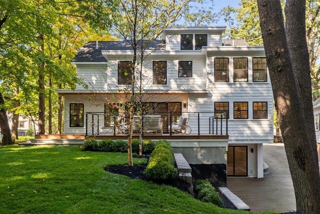 rear view of property featuring a wooden deck and a lawn