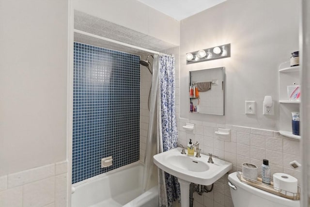 full bath with shower / tub combo with curtain, toilet, tile walls, and a sink