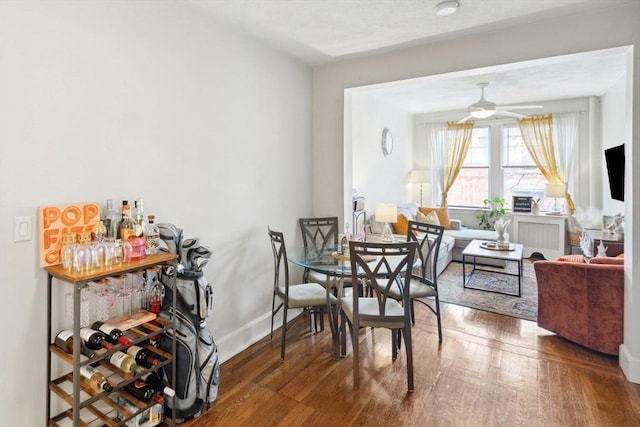 dining area with radiator, a ceiling fan, baseboards, and hardwood / wood-style flooring