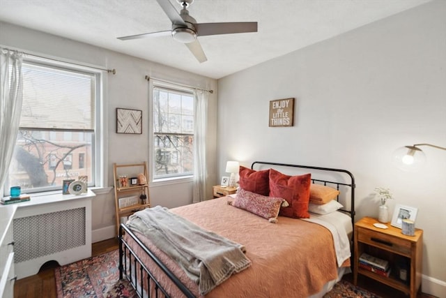 bedroom featuring wood finished floors, radiator, a ceiling fan, and baseboards