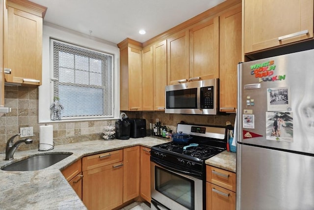 kitchen featuring a sink, stainless steel appliances, light stone countertops, and decorative backsplash