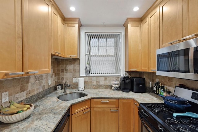 kitchen featuring light stone counters, a sink, range with gas cooktop, stainless steel microwave, and backsplash