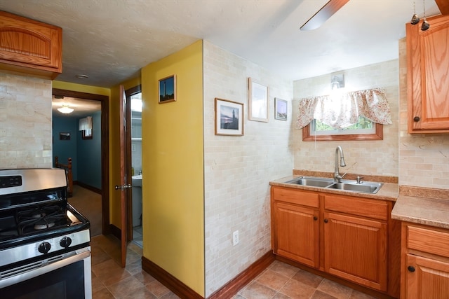 kitchen with tasteful backsplash, stainless steel gas stove, and sink