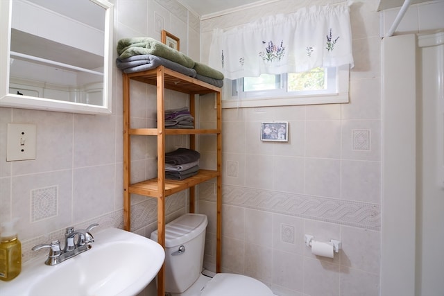 bathroom with toilet, sink, and tile walls