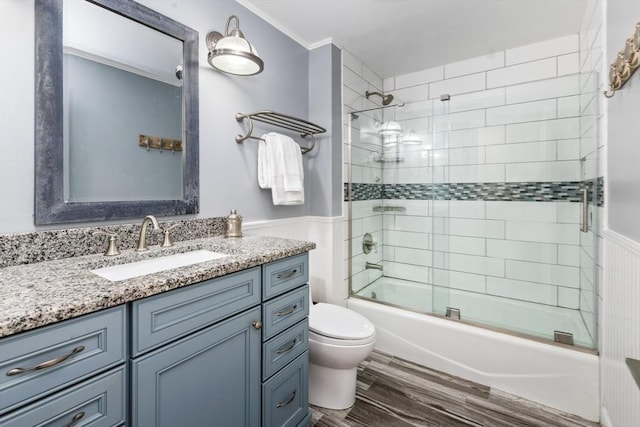 full bathroom featuring ornamental molding, vanity, shower / bath combination with glass door, wood-type flooring, and toilet