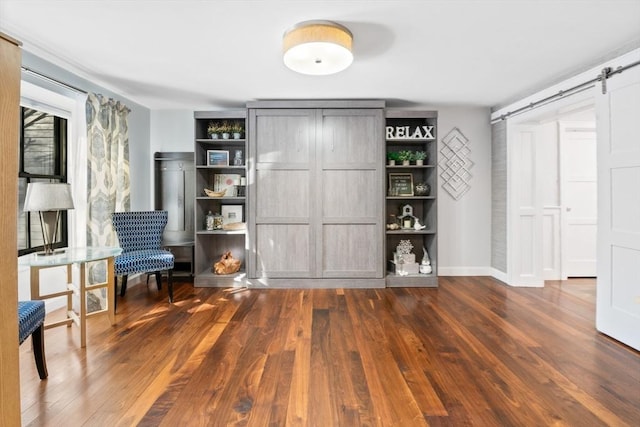 unfurnished room with a barn door and dark hardwood / wood-style floors