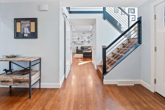 corridor featuring wood-type flooring and a barn door