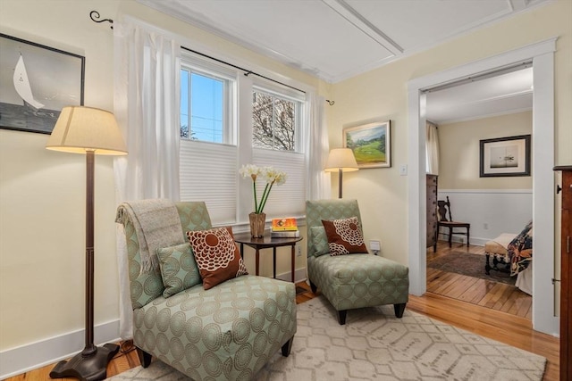 living area with crown molding and light wood-type flooring