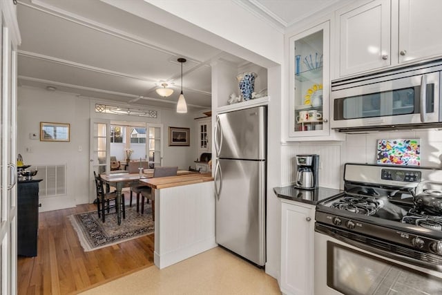 kitchen with white cabinetry, wooden counters, appliances with stainless steel finishes, pendant lighting, and backsplash