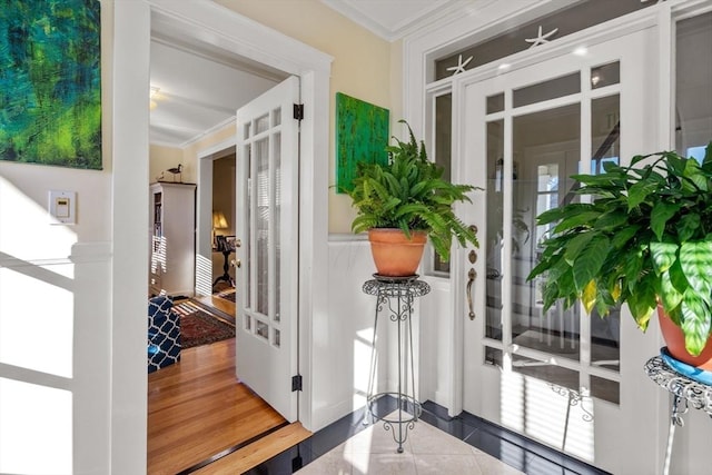 entryway with tile patterned flooring, crown molding, and french doors