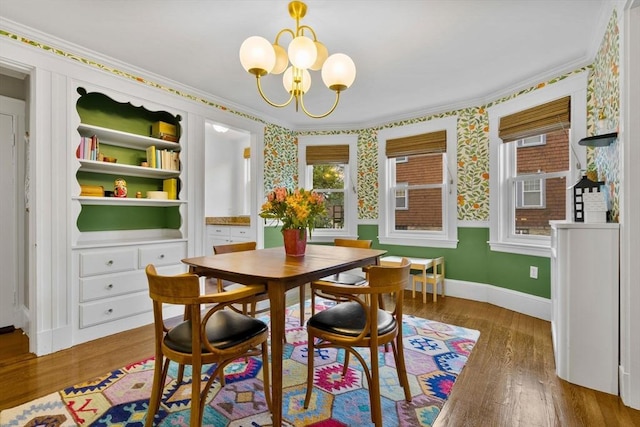 dining room featuring ornamental molding, a chandelier, wood finished floors, baseboards, and wallpapered walls