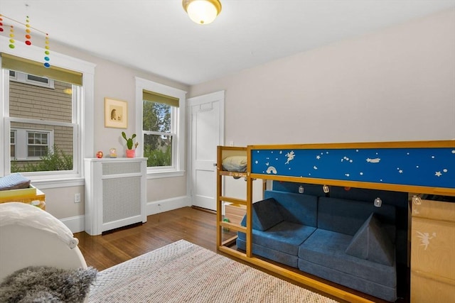 bedroom featuring radiator, wood finished floors, and baseboards