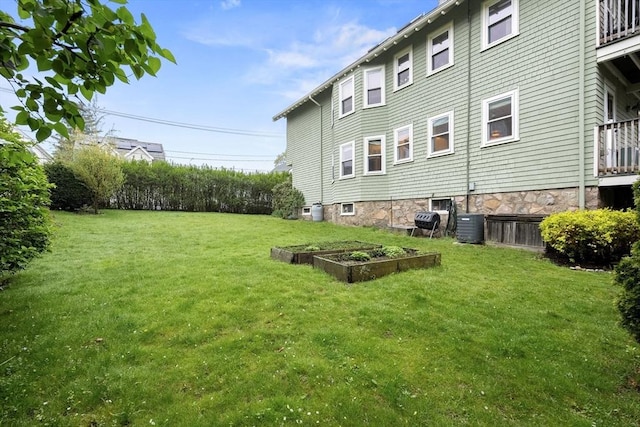 view of green lawn with a garden and central AC unit