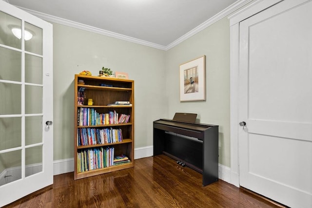 living area featuring wood finished floors, crown molding, and baseboards