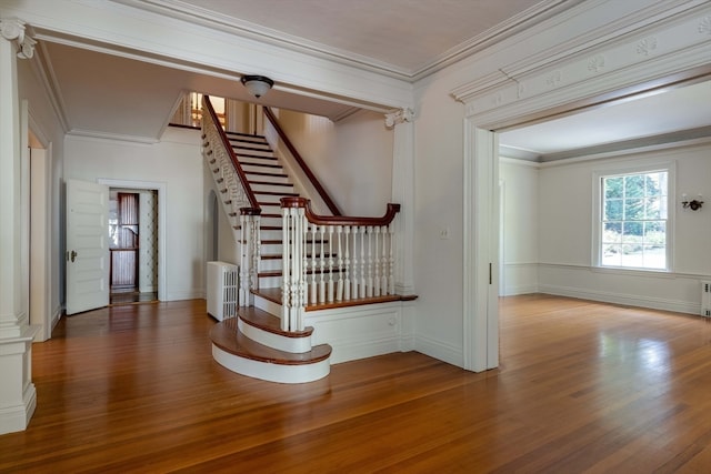 stairway featuring crown molding, radiator heating unit, and hardwood / wood-style flooring