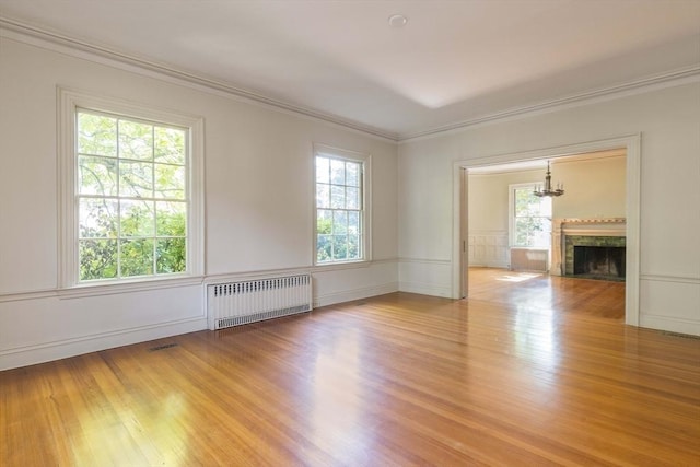 87 Hammond St, Newton, MA 02467 - spare room with radiator, wood finished floors, crown molding, a decorative wall, and a fireplace