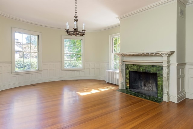 unfurnished living room featuring wood-type flooring, radiator, and a wealth of natural light