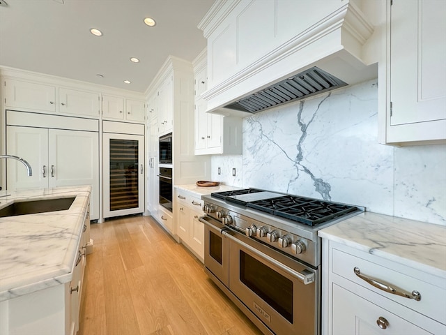 kitchen with light wood-type flooring, sink, appliances with stainless steel finishes, and white cabinets