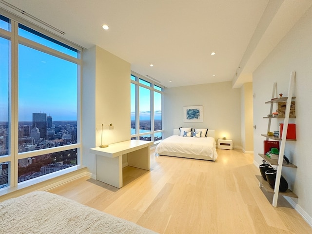 bedroom with a water view, light wood-type flooring, and a wall of windows