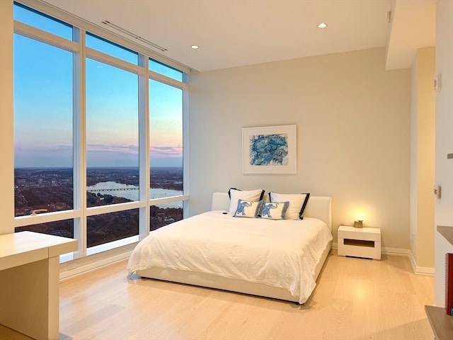 bedroom with light wood-type flooring and a wall of windows