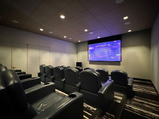 cinema room with a paneled ceiling and carpet flooring