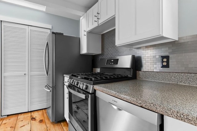 80 Lennox Rd Unit 1, Nahant, MA 01908 - kitchen with appliances with stainless steel finishes, white cabinets, backsplash, light wood finished floors, and dark countertops