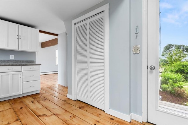 80 Lennox Rd Unit 1, Nahant, MA 01908 - kitchen with white cabinets, light wood finished floors, a baseboard radiator, dark countertops, and baseboards