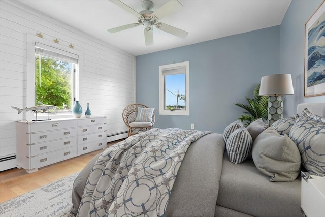 80 Lennox Rd Unit 1, Nahant, MA 01908 - bedroom featuring baseboard heating, light wood-style floors, ceiling fan, and wood walls