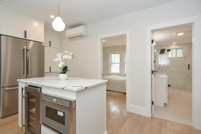 57 Garrison Ave Unit 57, Somerville, MA 02144 - kitchen featuring high quality fridge, a wall mounted air conditioner, beverage cooler, white cabinets, and light wood-type flooring