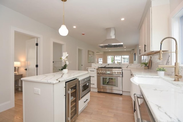 57 Garrison Ave Unit 57, Somerville, MA 02144 - kitchen featuring high end stainless steel range, wine cooler, wall chimney range hood, white cabinets, and light wood-style flooring