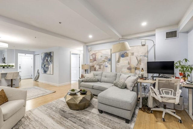 living room with light wood-style flooring, visible vents, an AC wall unit, and baseboards