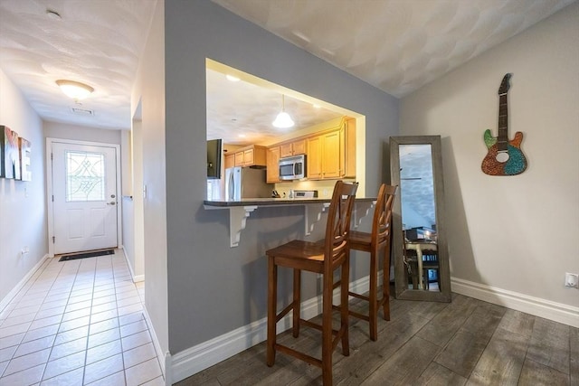 65 Bliss Ave Unit 4, Attleboro, MA 02703 - kitchen featuring appliances with stainless steel finishes, a kitchen breakfast bar, light wood-type flooring, and a peninsula