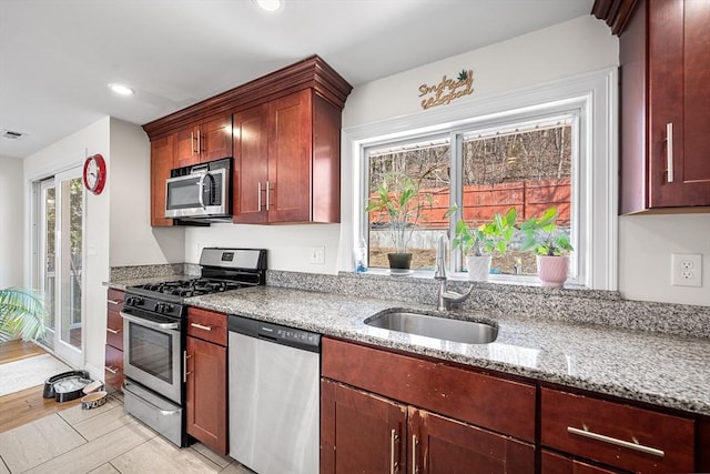 kitchen featuring light stone counters, stainless steel appliances, recessed lighting, visible vents, and a sink