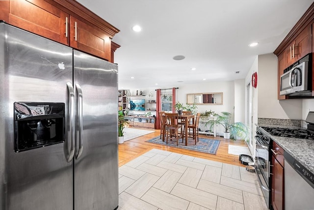 kitchen featuring appliances with stainless steel finishes, recessed lighting, light wood-type flooring, and light stone countertops