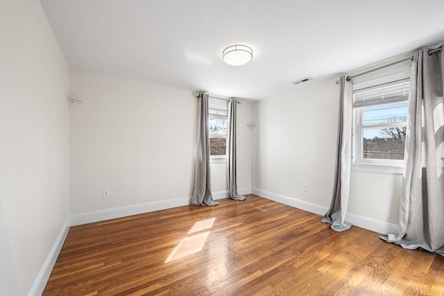 spare room with visible vents, plenty of natural light, and wood finished floors