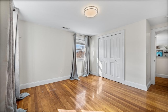 unfurnished bedroom featuring visible vents, baseboards, and wood finished floors