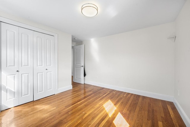 unfurnished bedroom with light wood-style flooring, baseboards, and a closet