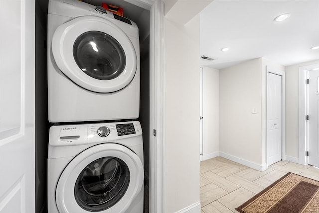 laundry room with visible vents, laundry area, stacked washer and clothes dryer, and baseboards