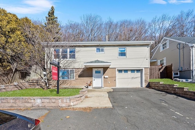 view of front facade featuring a garage, driveway, and fence