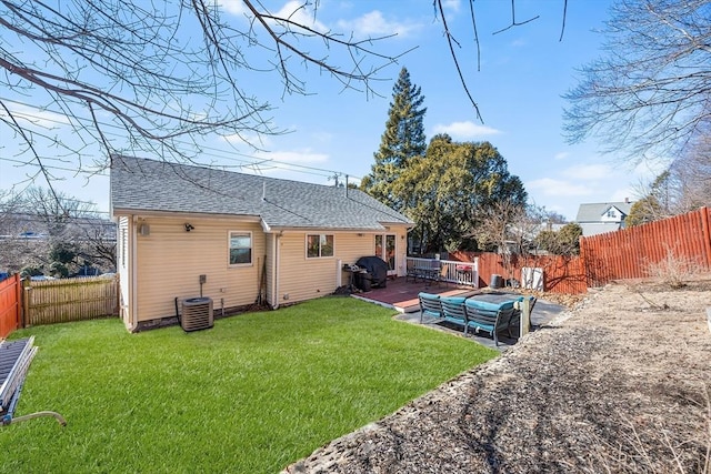 rear view of property with roof with shingles, a fenced backyard, a lawn, and central air condition unit