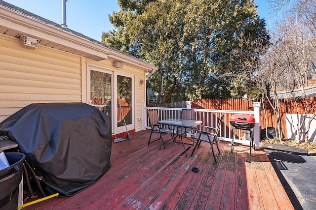 deck featuring outdoor dining area, area for grilling, and fence