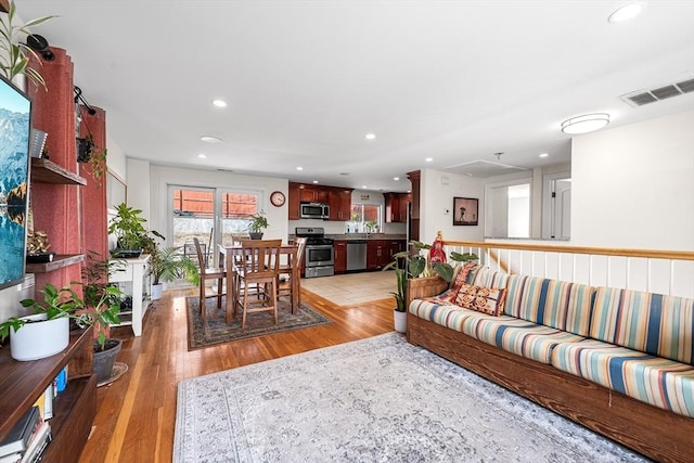 living area featuring light wood-type flooring, visible vents, and recessed lighting