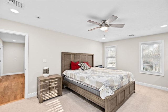 bedroom with multiple windows, light carpet, and ceiling fan