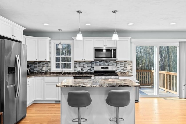 kitchen with hanging light fixtures, stainless steel appliances, and white cabinets