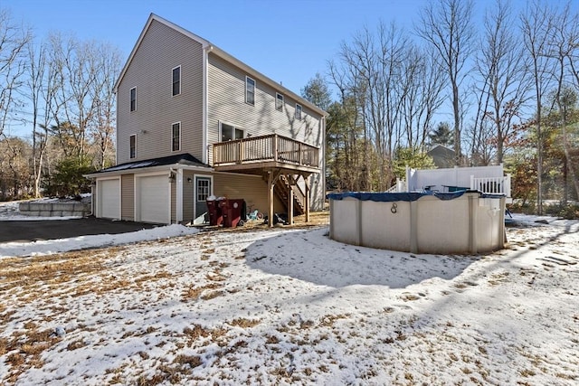 snow covered rear of property with a pool side deck and a garage